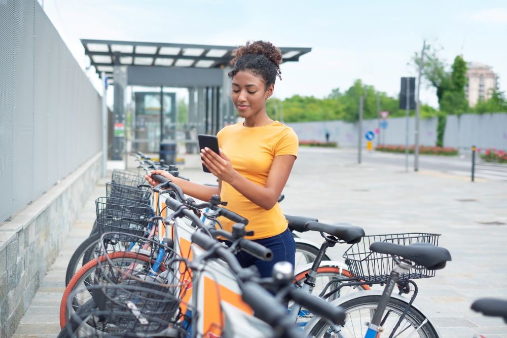 Frau am Handy an einer Bike Sharing Station