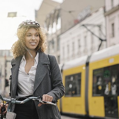 Frau mit Fahrrad und Helm vor Tram